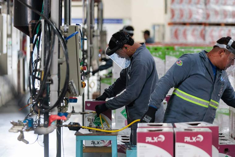 Operadores envasando fluido refrigerante na fábrica RLX